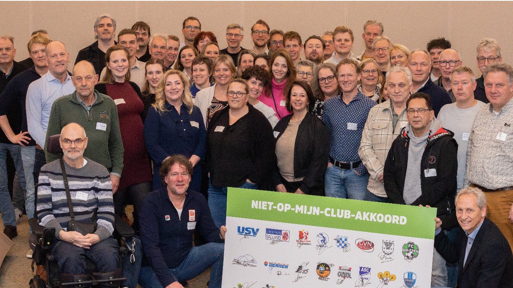 Jan Uitslag (rechtsonder) en Erik Beuker, projectleider sociaal veilige sport bij NOC*NSF (links naast het akkoord) poseren samen met vertegenwoordigers van de 29 sportclubs bij het Niet op mijn club-akkoord.