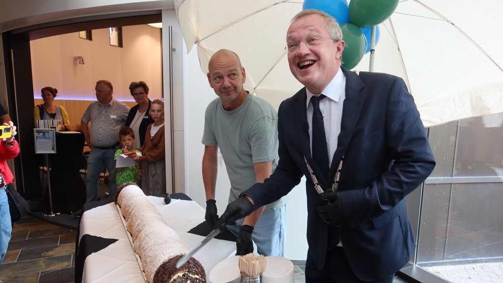 Samen met Willem Timmer zet burgemeester Michael Sijbom het mes in het langste Hulster Rolletje. 
