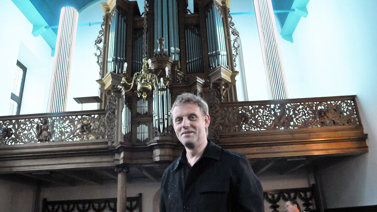 Peter Vonk voor de lichtzuilen die hij in de kerk van Pieterburen creëerde.