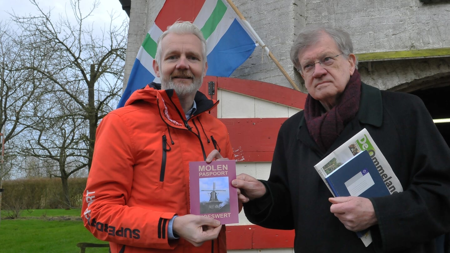 Wethouder Bé Schollema (links) ontvangt een molenpaspoort van molen Joeswert in Feerwerd uit handen van molenvoorzitter Hansmaarten Bolle.