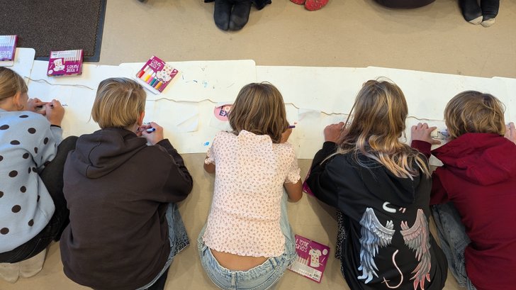 Kinderen van obs Brunwerd werken aan een vlaggenlijn met daarop hun toekomstwensen. 