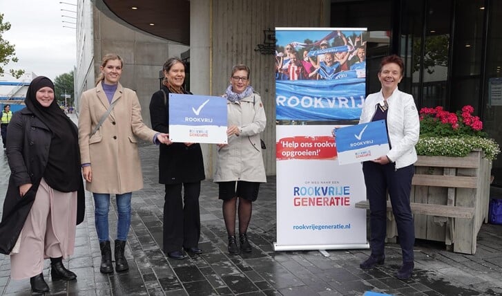 Wethouder Roelie Bosch (rechts) bij de tegel voor het Stadhuis. Links vertegenwoordigers van Het Netwerk Rookvrije Generatie Almere. (Foto: gemeente Almere)