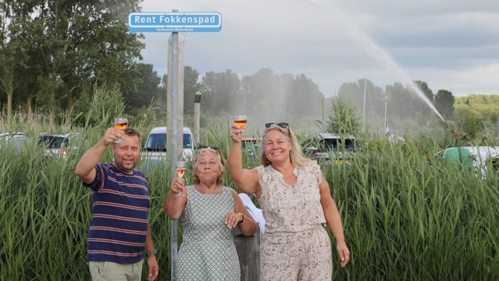 Tineke (midden), Sander en Jeanine Fokkens van camping Waterhout onthulden zondag tijdens de viering van het jubileum een straatnaambordje voor hun overleden man en vader Rent Fokkens. (Foto: Studio Rotgans/ Rinus Lettinck)