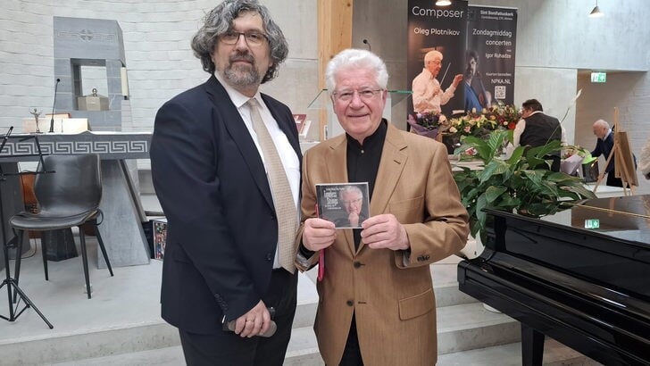 Violist Igor Ruhadze van NPKA verraste Oleg Plotnikov met het eerste exemplaar van hun nieuwe cd Timeless Strings. (Foto: Almere DEZE WEEK)
