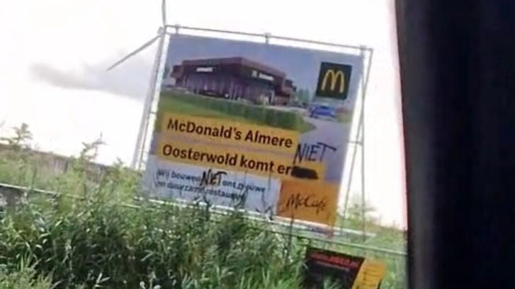 Het bord dat de komst van de McDonalds aankondigt werd beklad door tegenstanders en later vernield. (Foto: aangeleverd)
