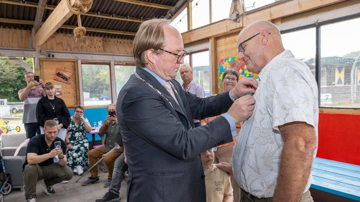 Burgemeester Hein van der Loo spelt de onderscheiding op bij Frits Smelt. (Foto: Maarten Feenstra)