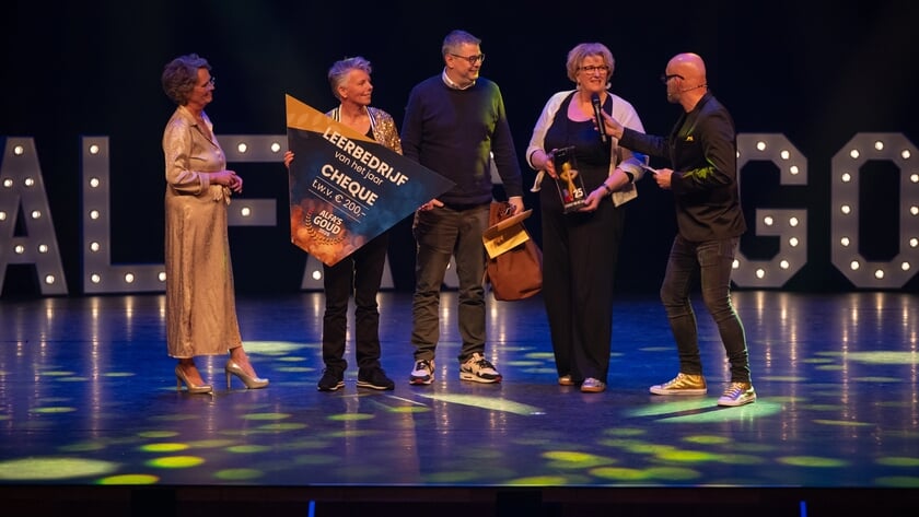 De delegatie van het wijkleerbedrijf neemt de prijs in ontvangst.