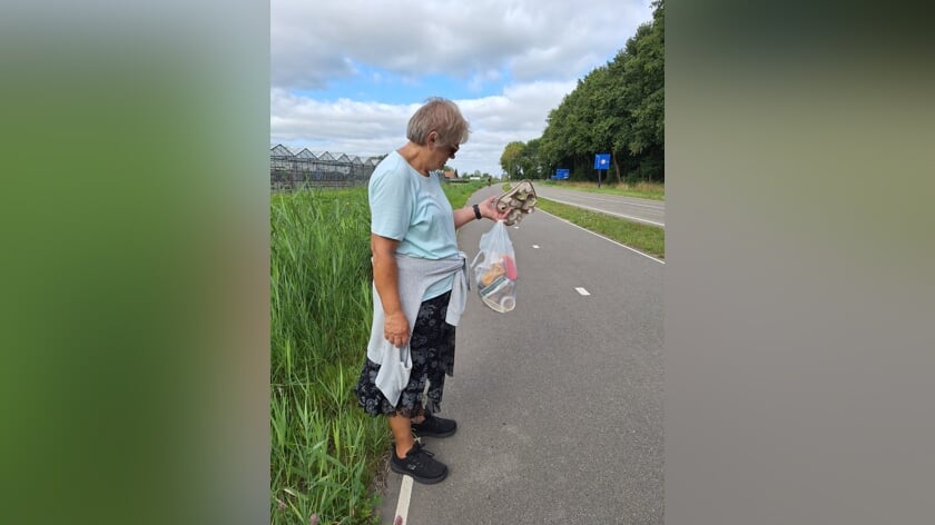 Sjanie raapt al wandelend troep van de straat