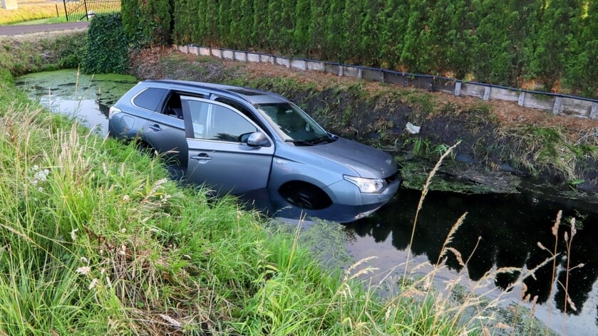 Auto de sloot in met twee kinderen