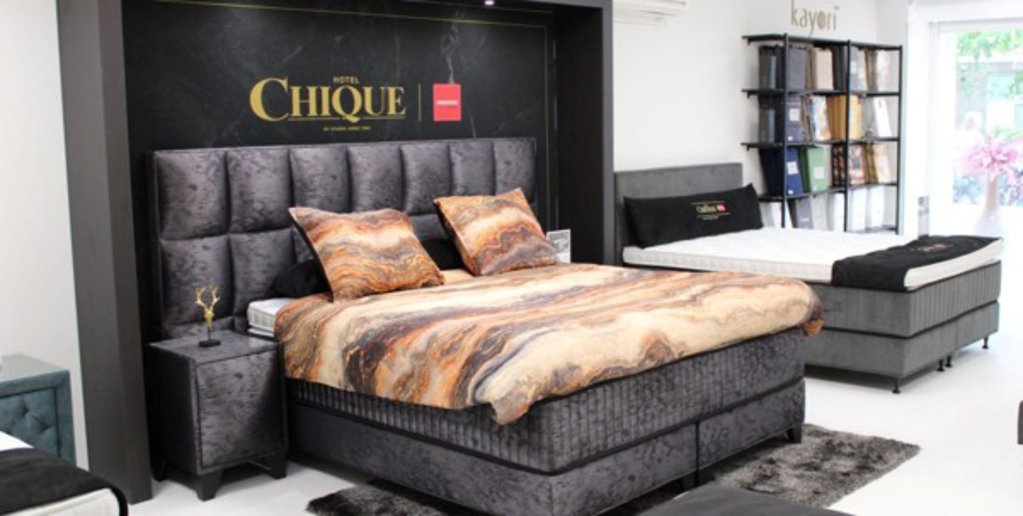 Een boxspring met hoofdbord, matras en topper.