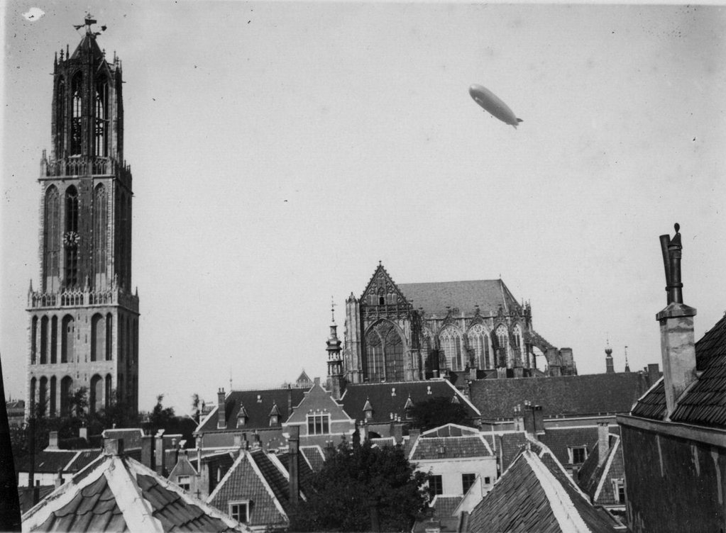 Gezicht op de Domkerk en de Domtoren (Domplein) te Utrecht; vanuit het zuiden met in de lucht het luchtschip Graf Zeppelin.