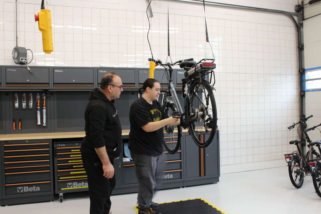 Twee deelnemers van het voorschakeltraject onderzoeken een fiets.