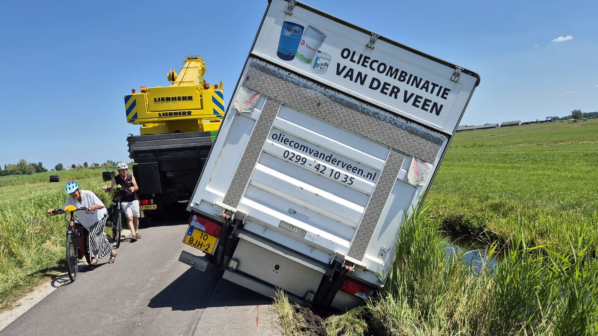 Volgeladen vrachtwagen met olie gekanteld op de dijk bij Zuiderwoude