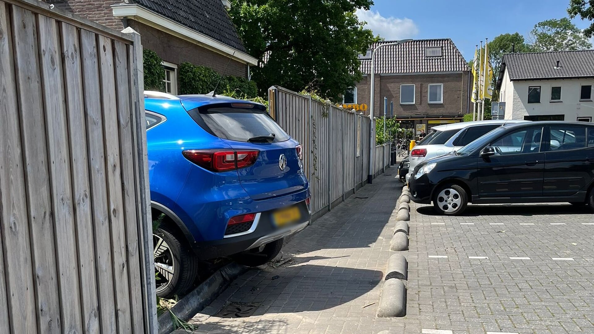 Auto rijdt achtertuin in bij supermarkt in Maaskantje