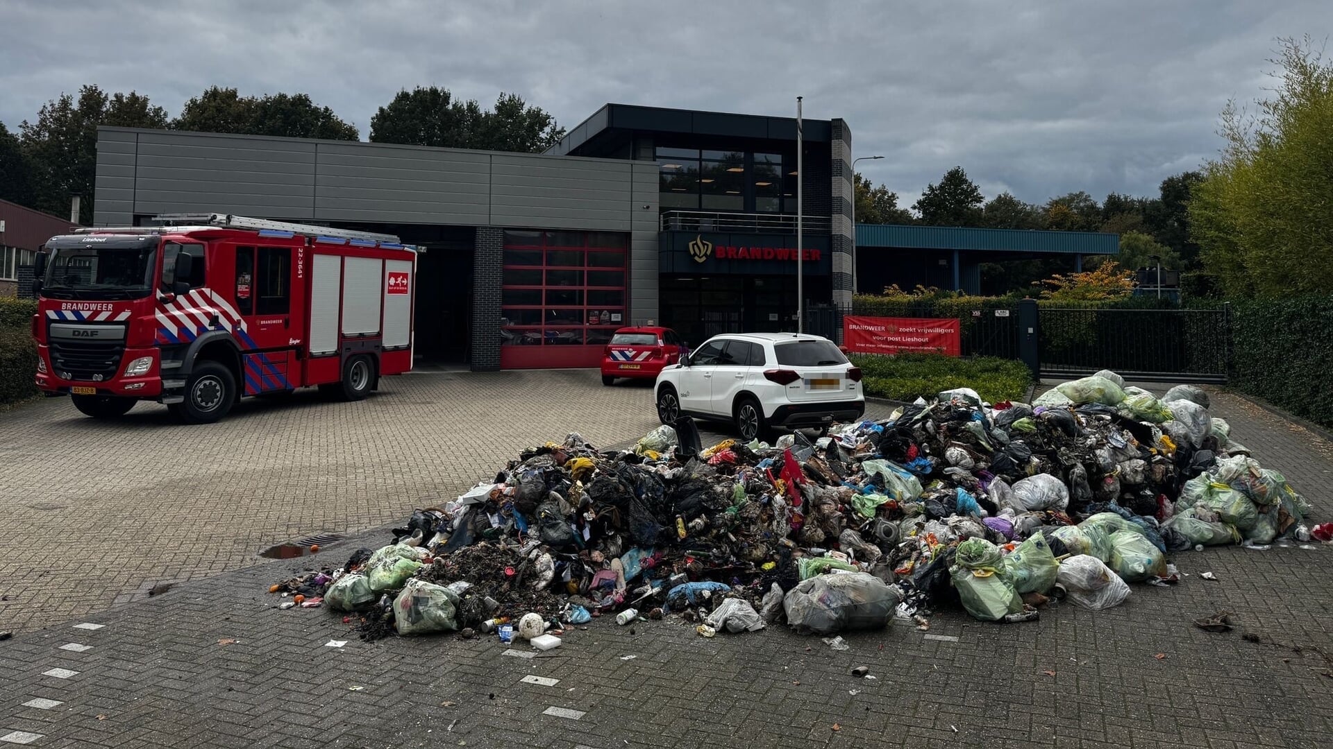 Vuilniswagen kiept brandende lading op parkeerplaats brandweerkazerne Lieshout