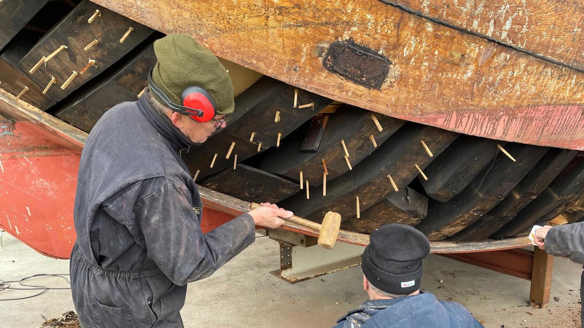 De UK 12 staat in de steigers in Workum; groep vrijwilligers maakt de botter klaar voor nieuw seizoe